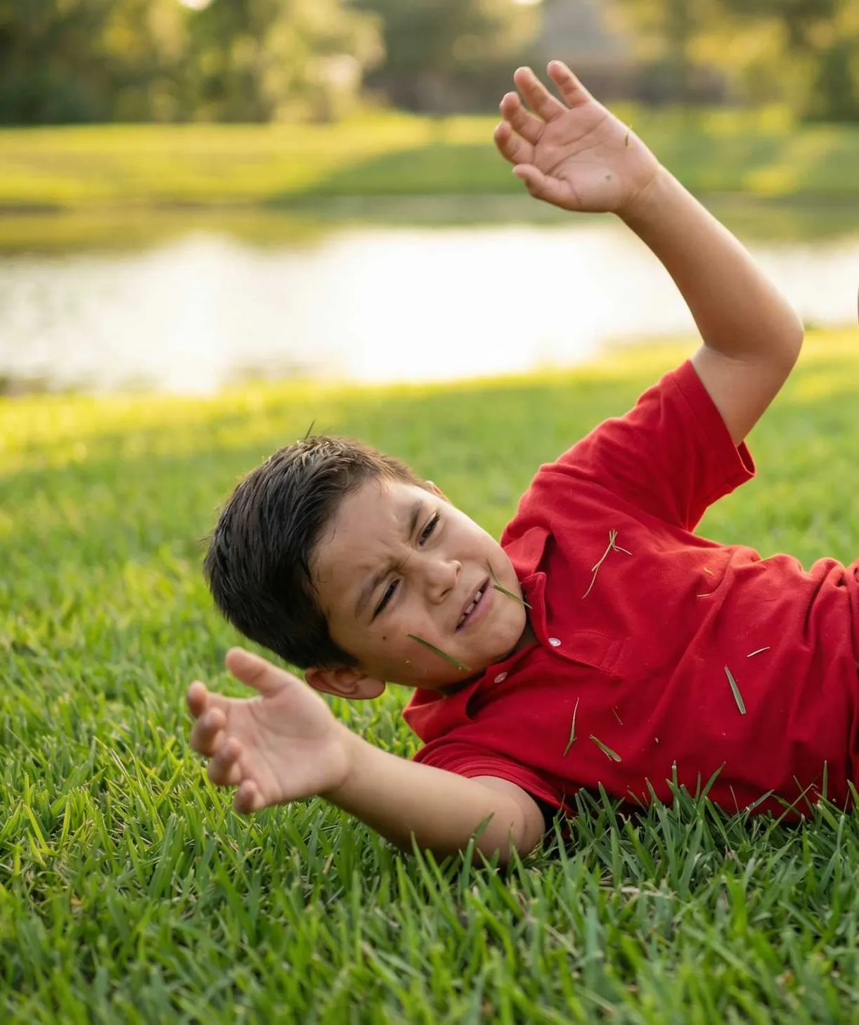 Boy lying on the grass holding his head after a fall
